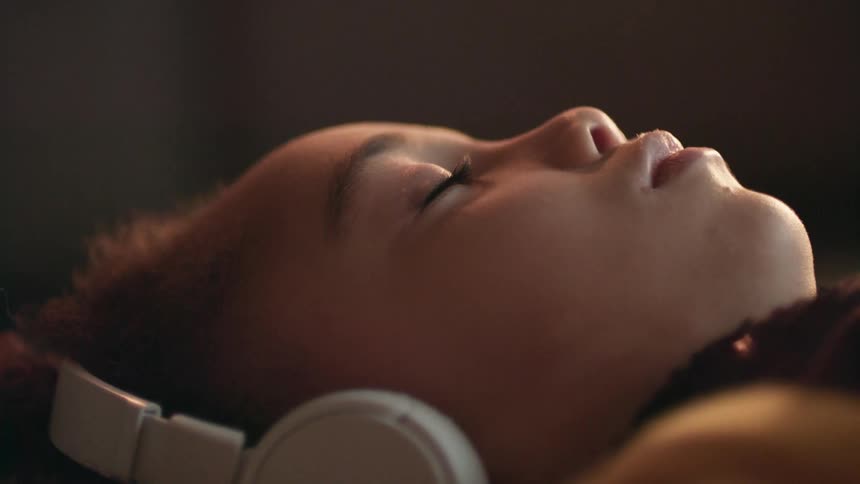 A child is listening to music and wearing headphones