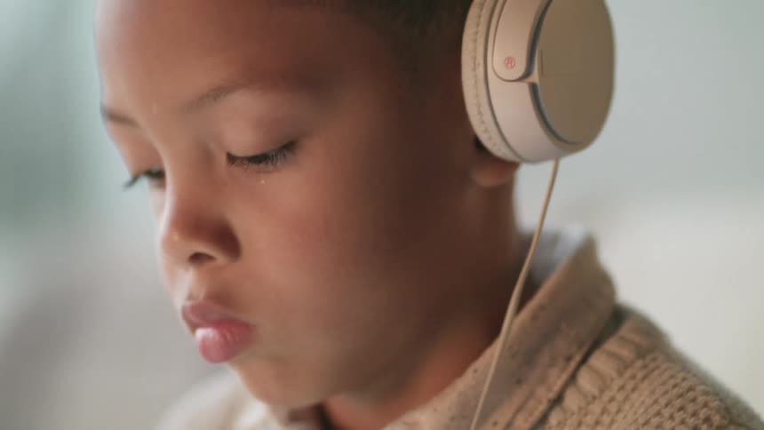 A young boy swiping on a tablet while wearing headphones