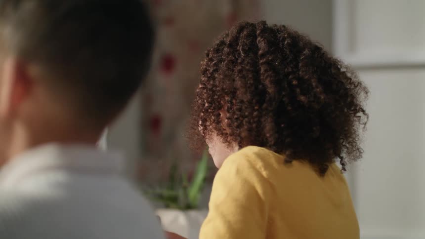 Young girl eating cereal for breakfast in the kitchen at home next to her brother