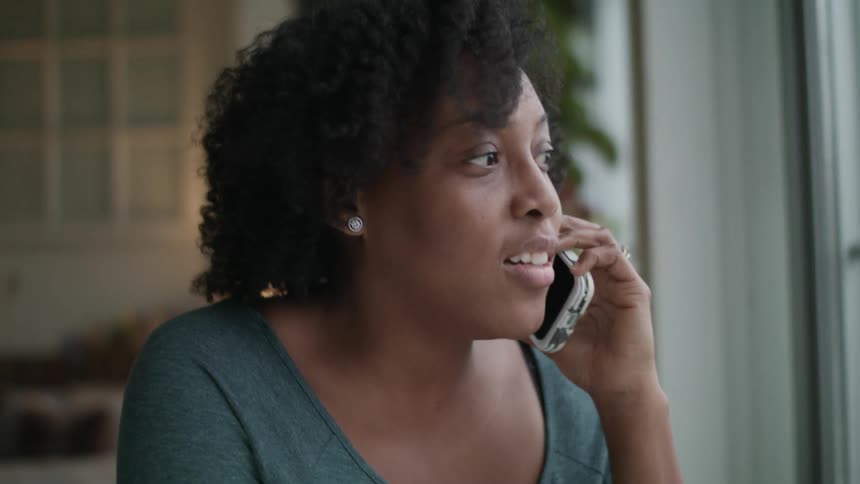 A woman is talking on her cell phone by the window