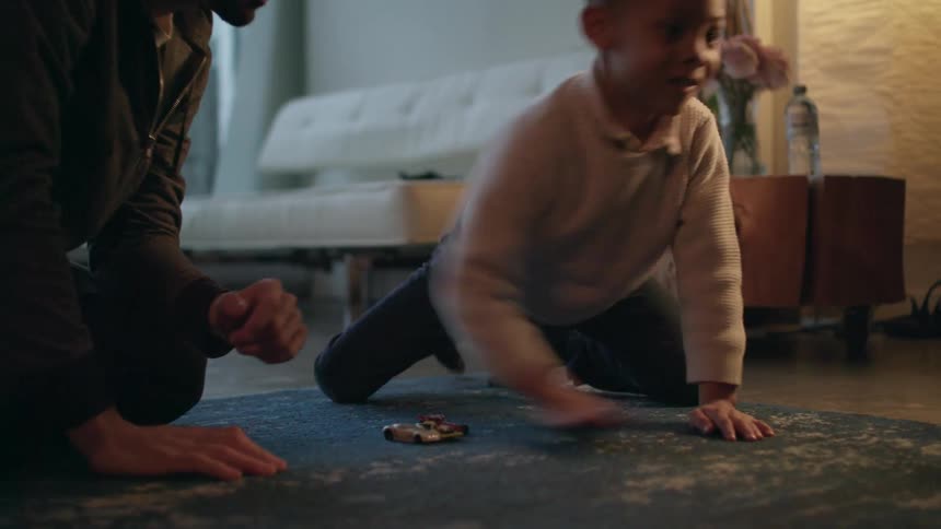 Father and son playing with toy cars over the carpet on the living room at home