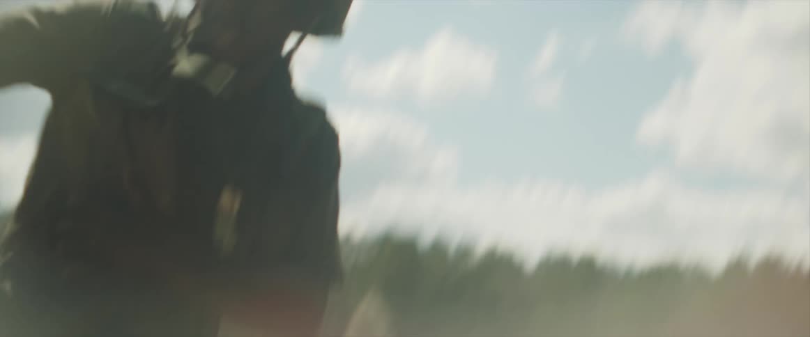 A man with a military uniform and a helmet running with trees the sky and clouds in the background