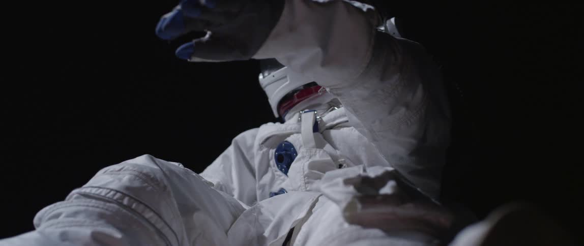An astronaut is floating in a black area