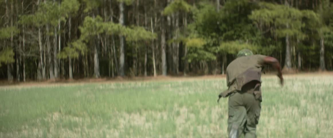 Wounded black soldier running in a field towards the woods