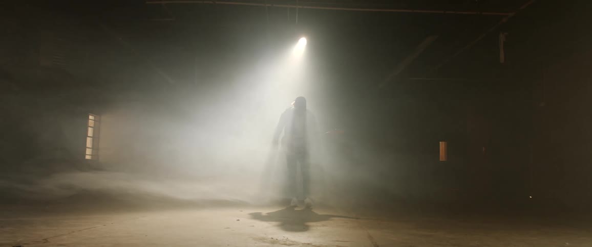 A musician with a guitar sways to music with a spotlight shining down on him