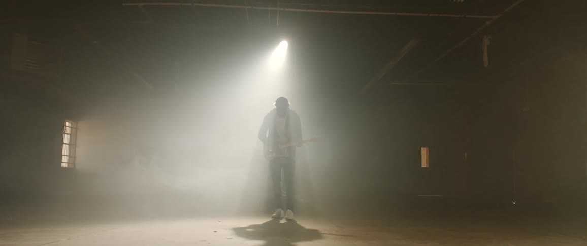 A silhouette of a person in a room playing a guitar