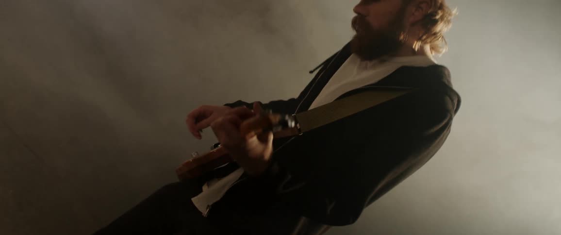 A man plays guitar with a light and smoke behind him
