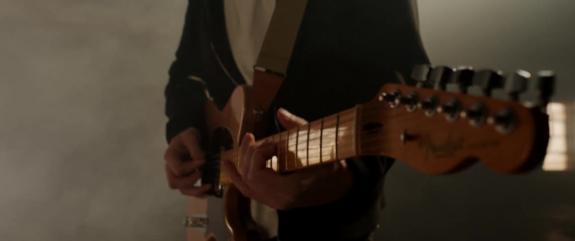 A man playing an electric guitar in a dimly lit room filled with smoke