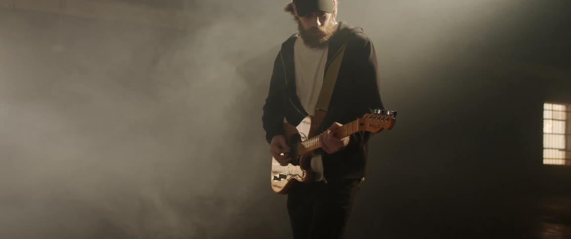 Fog swirling around a man playing an electric guitar