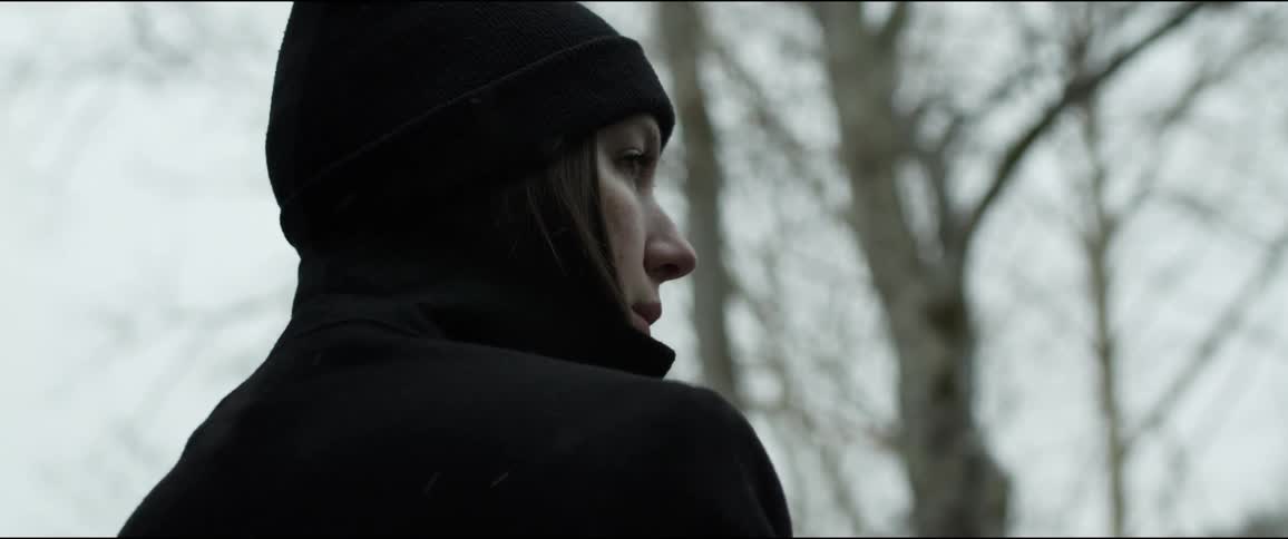 A woman is standing outdoors and wearing a hat
