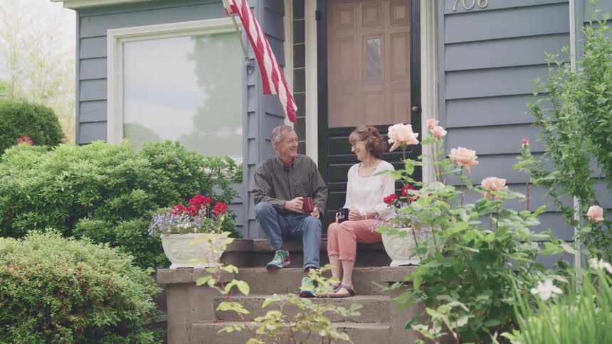 A man and woman sit together and have a pleasant chat on the steps in front of a house