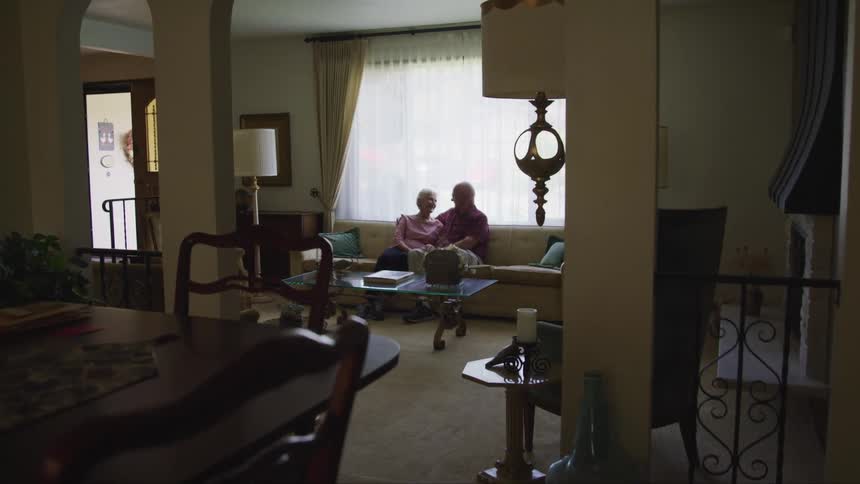A man and woman are sitting on a couch in their house