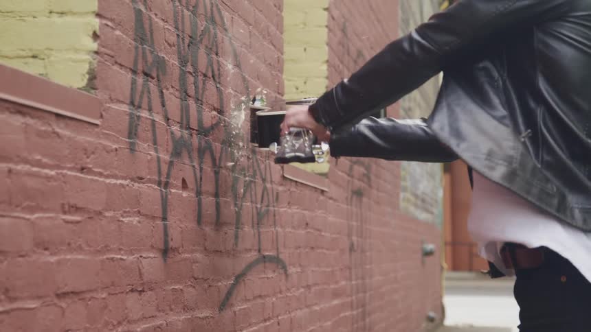 Angry musician smashing acoustic guitar against brick wall