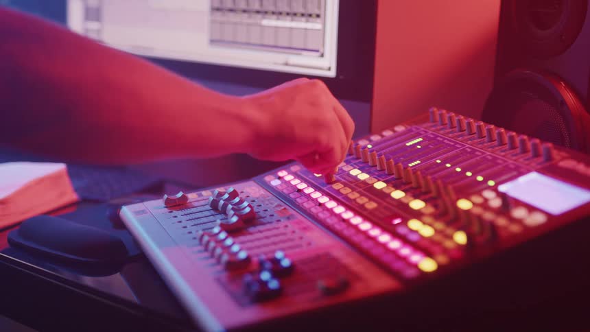 A man turns a knob on a soundboard