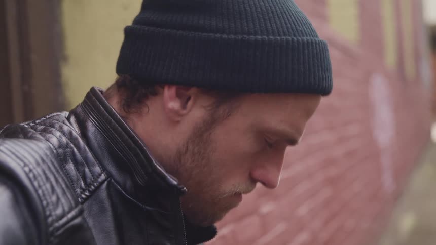 A man stands on a street corner and plays a guitar