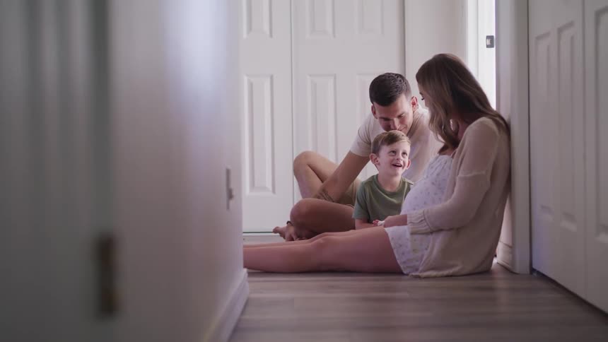 A man a woman and a boy sitting on the floor of a hallway