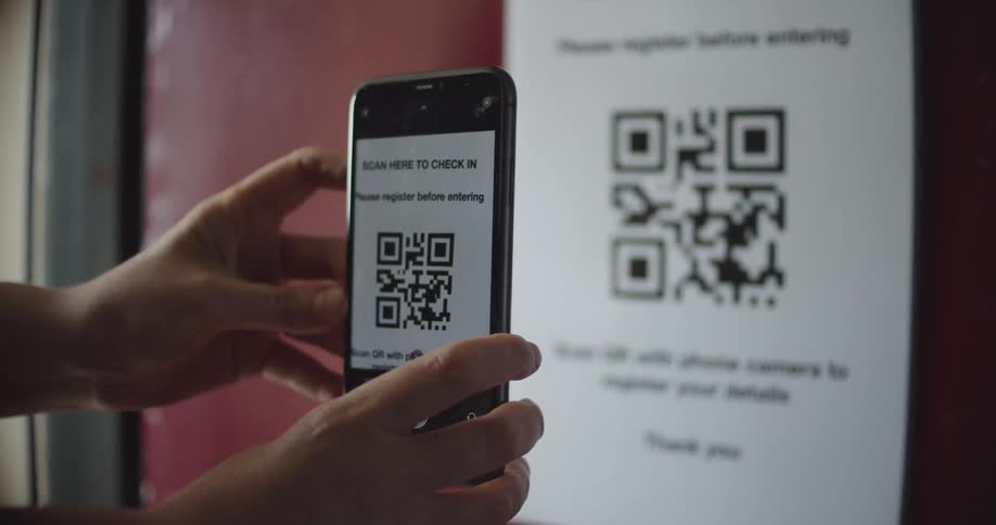 A person uses a smartphone to scan a qr code on a sheet of paper posted on a wall