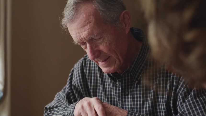 Elderly couple sitting on the table at home solving a jigsaw puzzle together