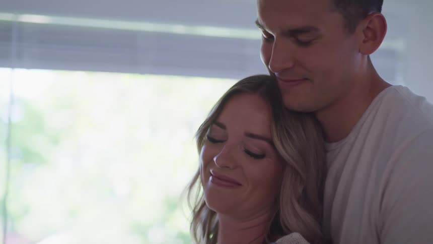 Young couple happily hugging in a room at home