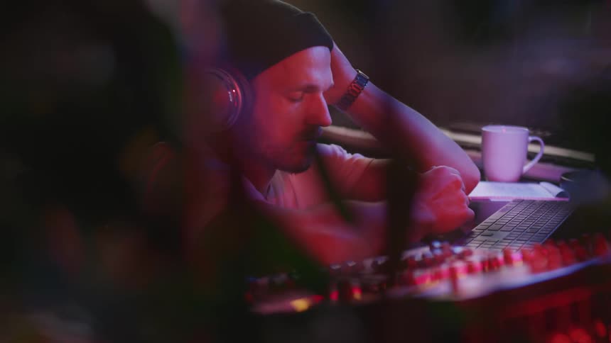 Musician composing and mixing music on a computer in a studio