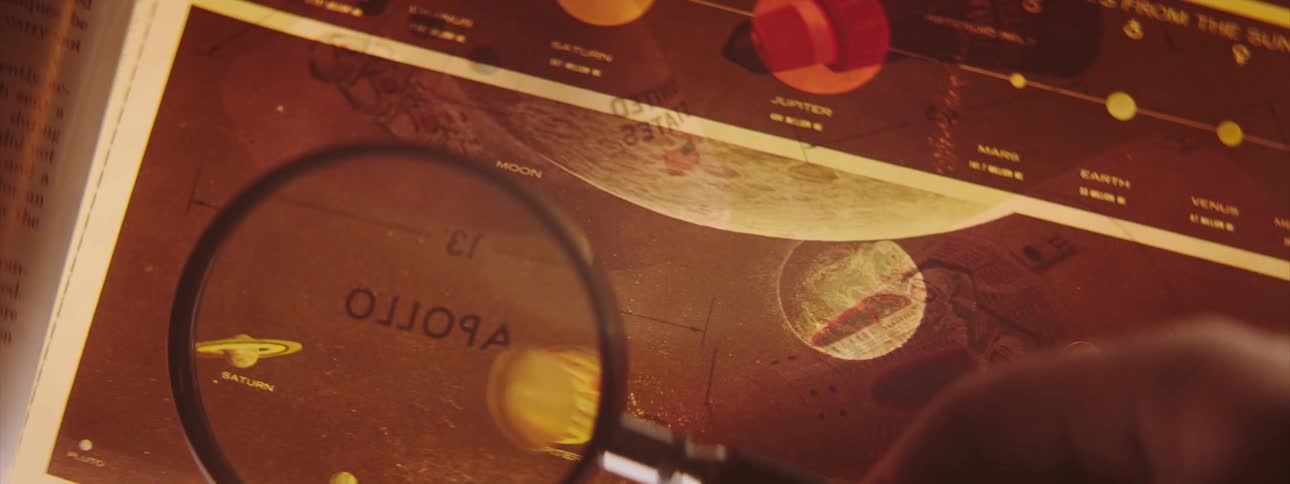 A person in a room looking at a book with a magnifying glass