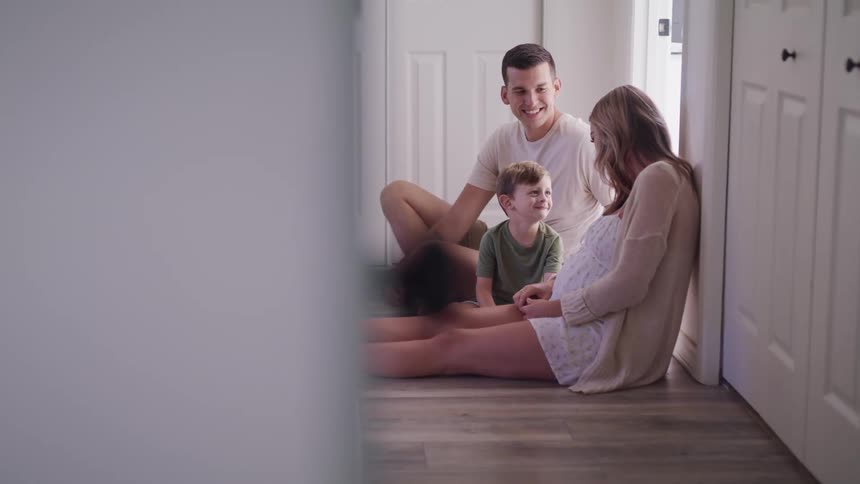 A man a woman and a boy sitting on the floor of a hallway
