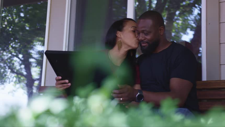 A wife kissing her husband looking at a picture