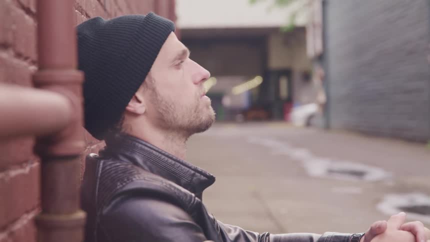 A man sits in the empty alley against the wall
