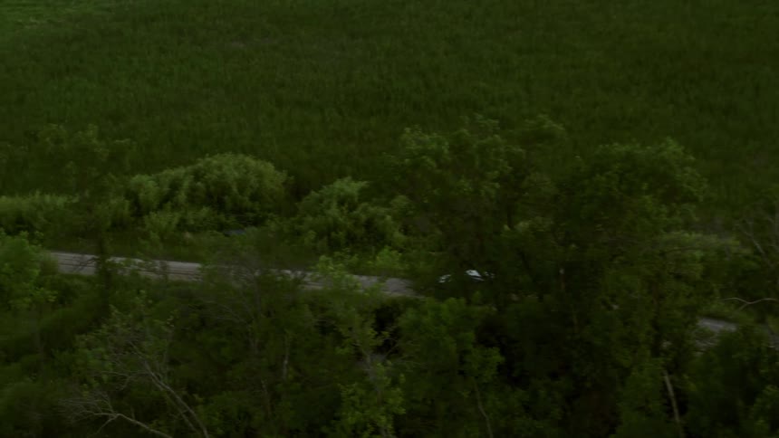 White car driving over a dirt road on a rural area at evening