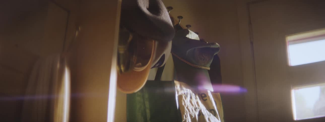Hats hanging from hooks on a rack indoors