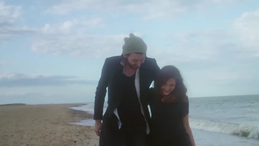 Young couple hugging and lauging while walking on the coast near the ocean
