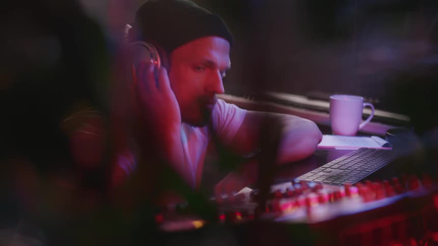 Man listening to sound over headphones adjusts settings on panel