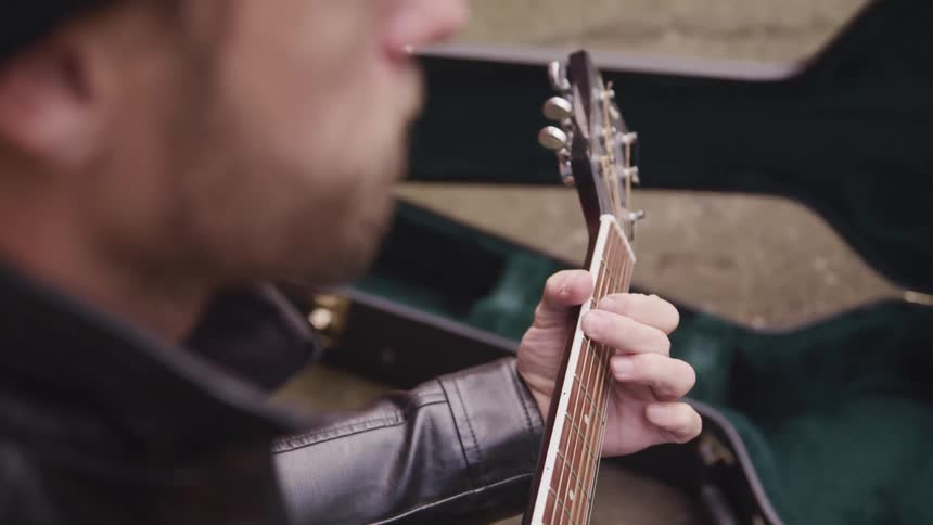 A man is playing a guitar outdoors