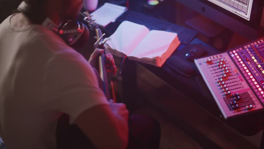 A man sits down with his guitar and plays