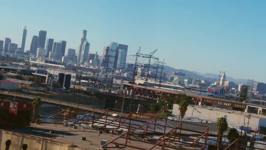 An aerial view of factories and refineries with a city skyline in the distance