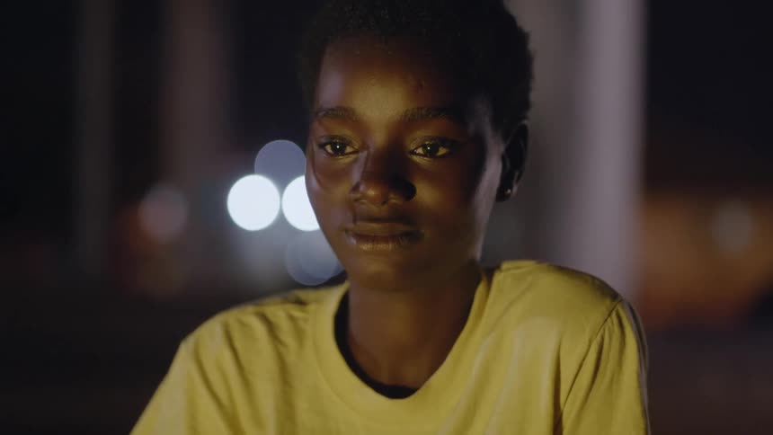 A young girl smiles as she sits in the glow of the light