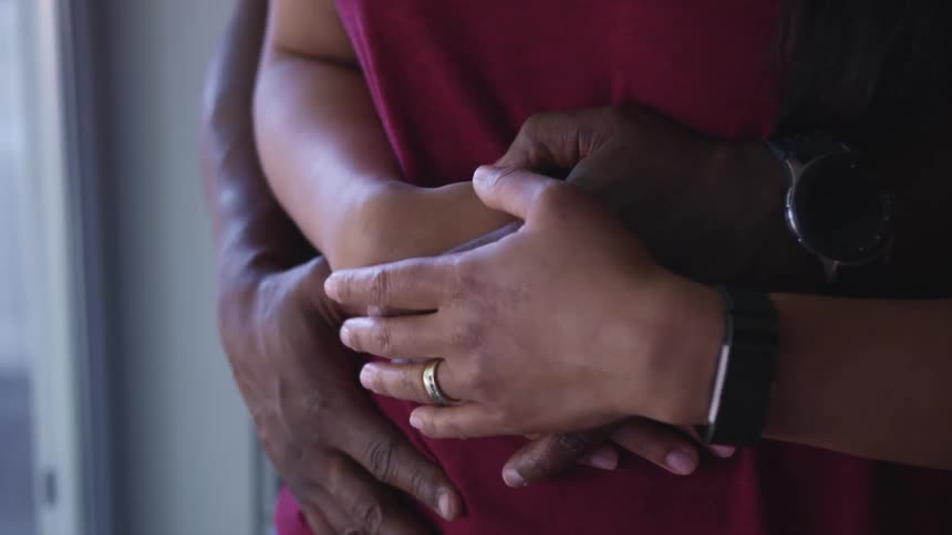 A man and a woman in a room hugging with rings and wristwatches