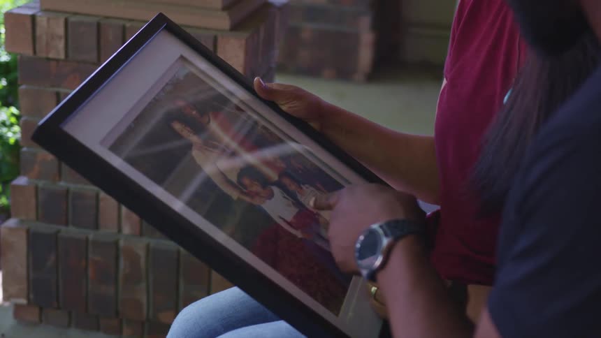 A couple sit on the porch looking at a photograph