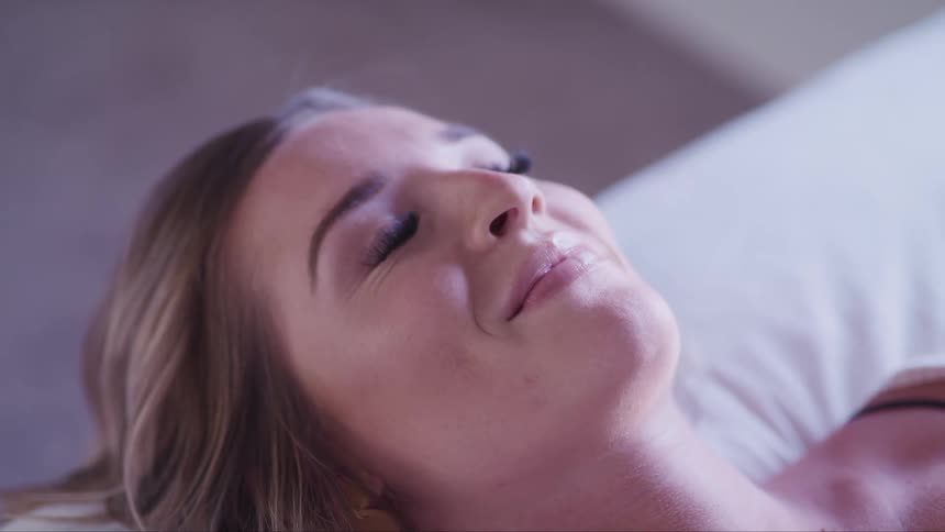 A woman smiles in her sleep and then opens her eyes