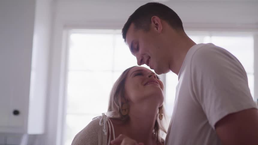 A man and woman are kissing indoors during the day