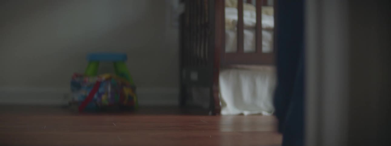 A child in pajamas runs into their bedroom with an adult slowly behind them