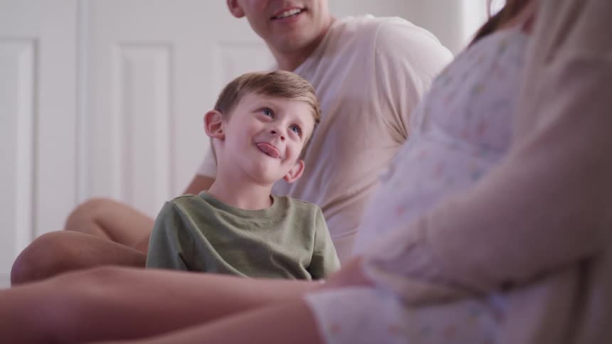 A little boy smiles as he sits at home with his mom and dad