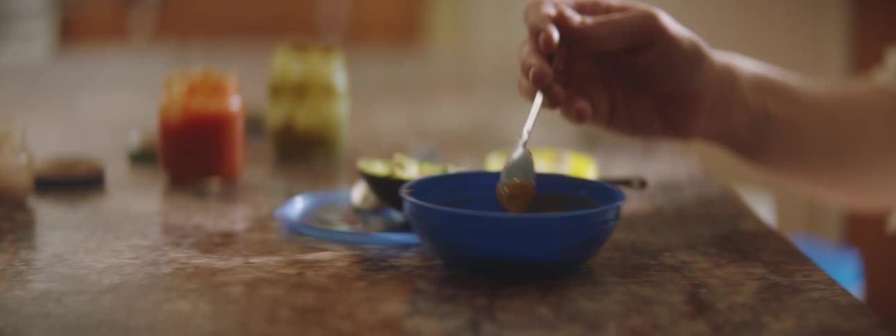 A woman in a room holding a child mixing baby food in a bowl