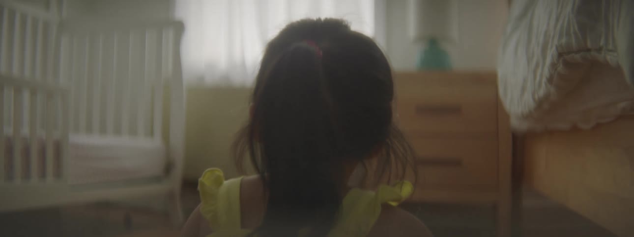 Small girl wearing a yellow dress sitting in the floor of the bedroom at home