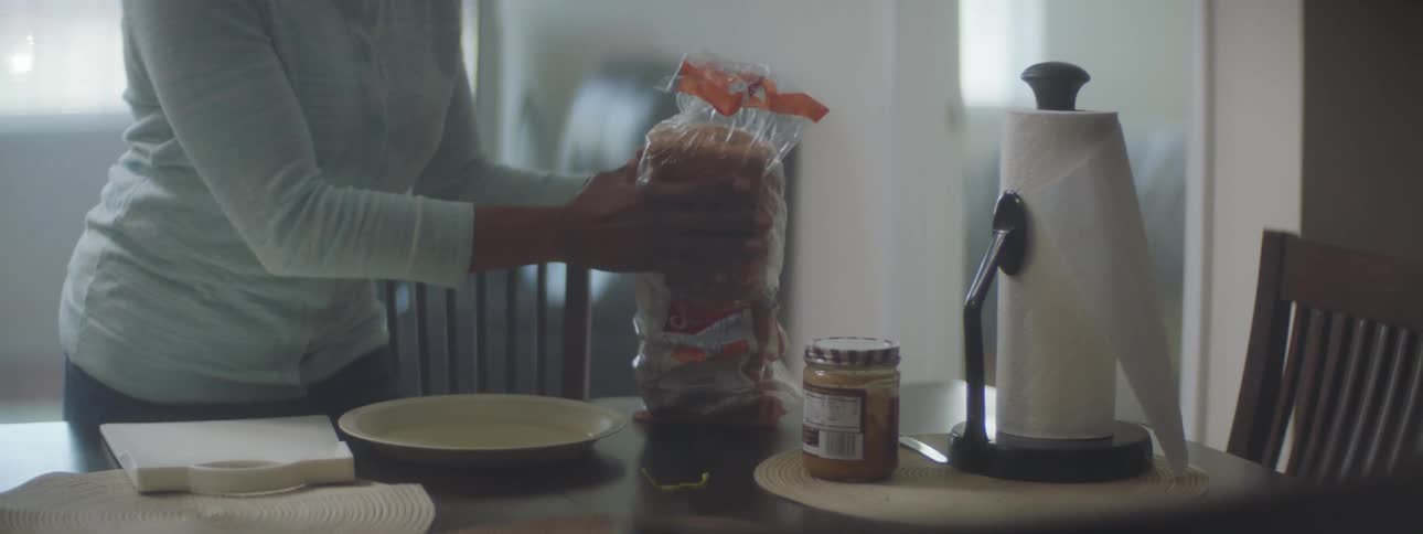 A woman opening a loaf of bread in a home kitchen