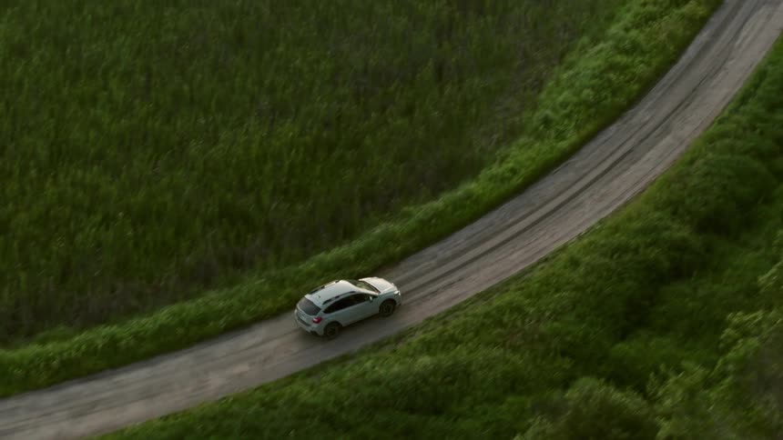 Silver van is traveling on rural road through forested area