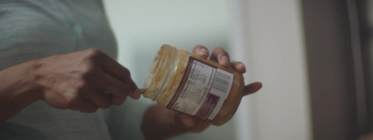 A man makes a peanut butter sandwich at home