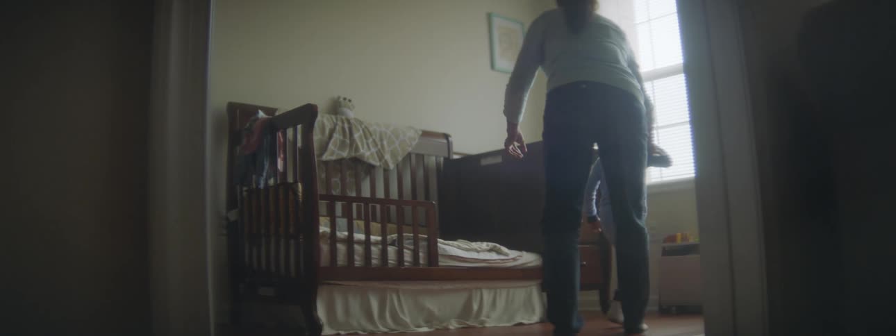 A mother chasing a young son into a bedroom with a crib