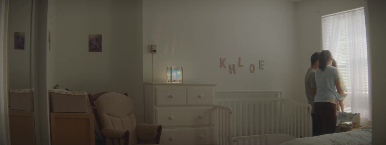 Parents hold their child by the window in baby bedroom