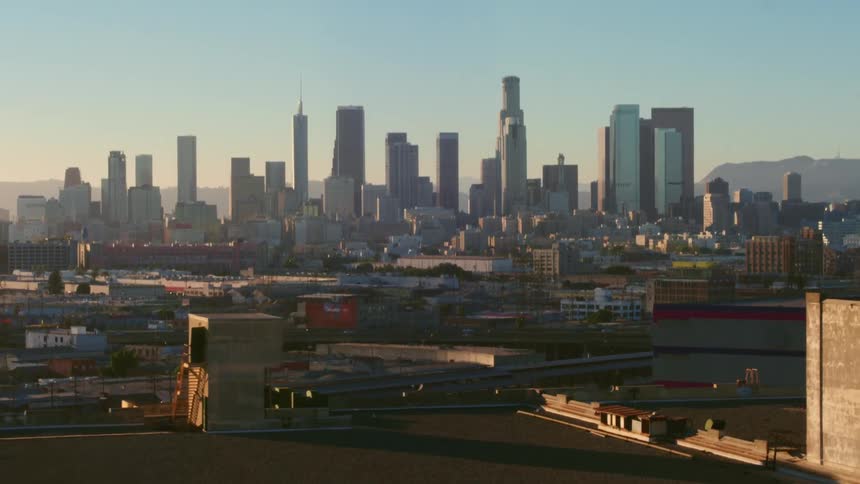 An aerial view of buildings in a city with a traffic and a skyline behind them
